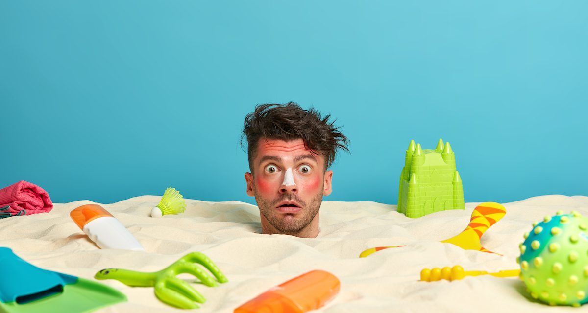 young-man-head-with-sunscreen-cream-face-surrounded-by-beach-accessories